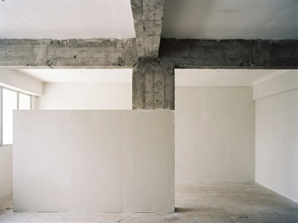 A T-shaped concrete beam crossing a ceiling above a bare partition wall