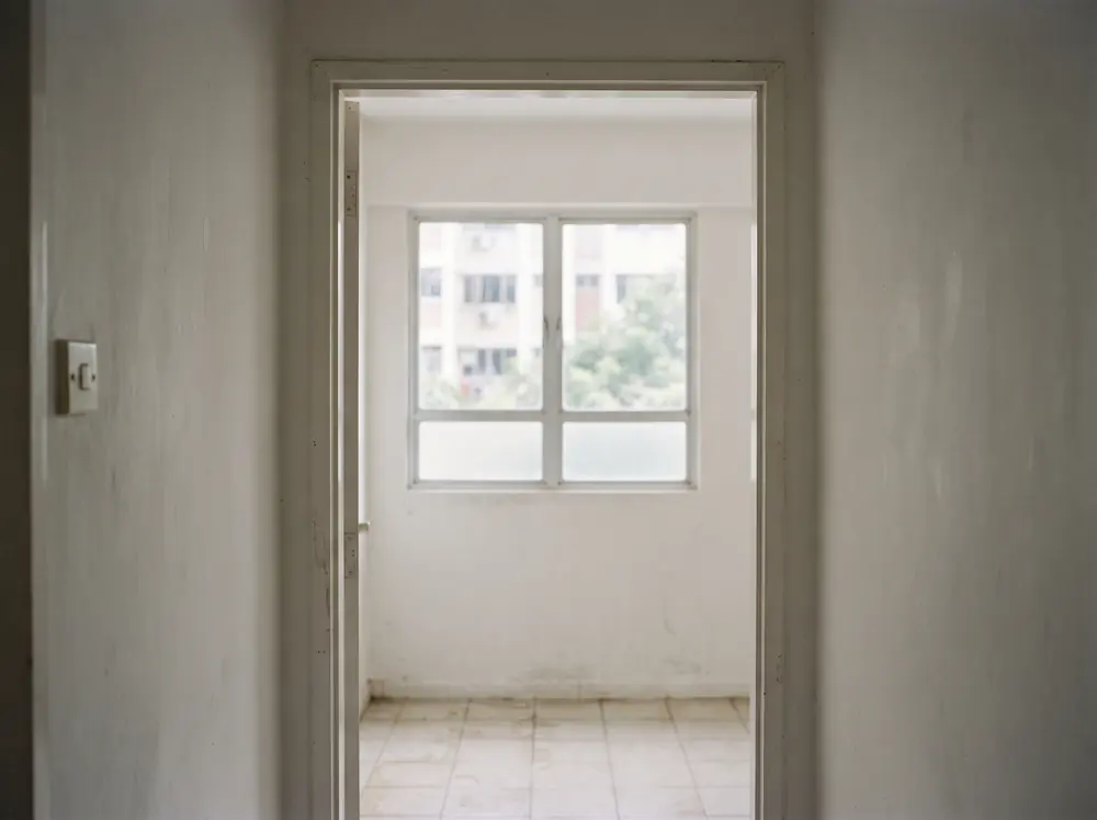 An empty bedroom doorway framing a bare window wall