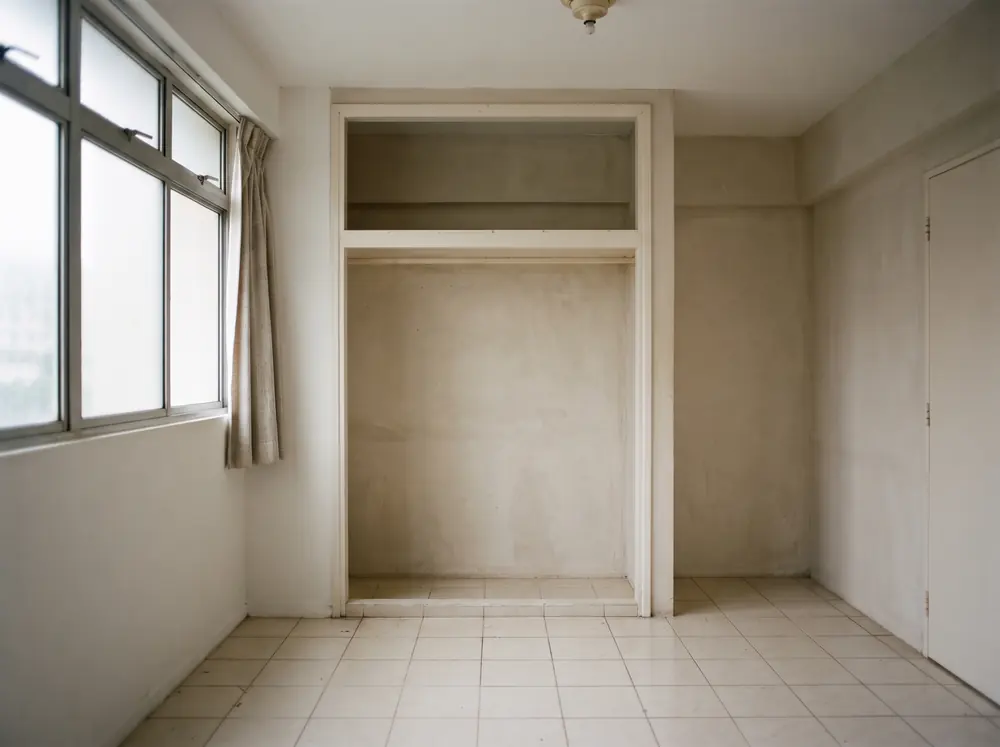 An empty bedroom with a bare wardrobe recess