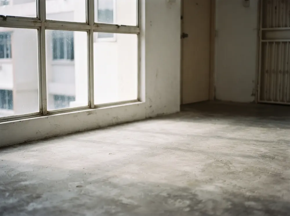 Window light falling across an untreated screed floor
