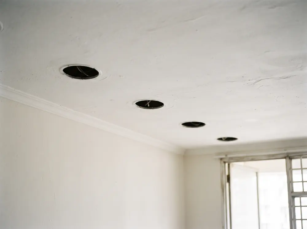 A bare ceiling with recessed downlight cutouts and no fittings