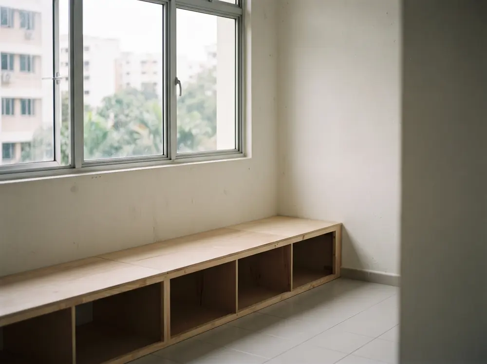 A bare window wall with a built-in bench carcass beneath it