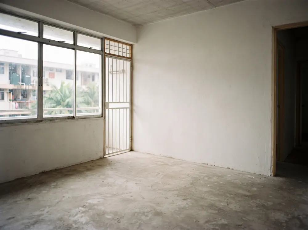 An empty apartment room with bare screed floor