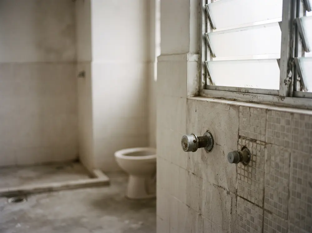 A bare bathroom with capped plumbing stubs and window light